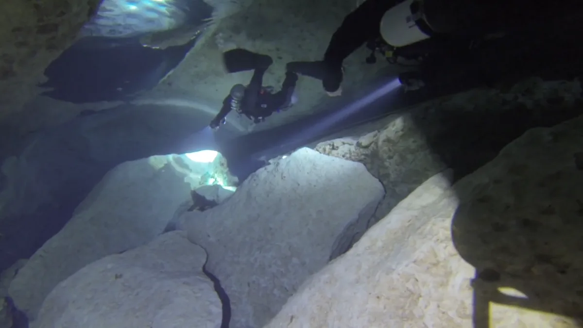 Buceador de cuevas en configuración sidemount navegando junto a la línea